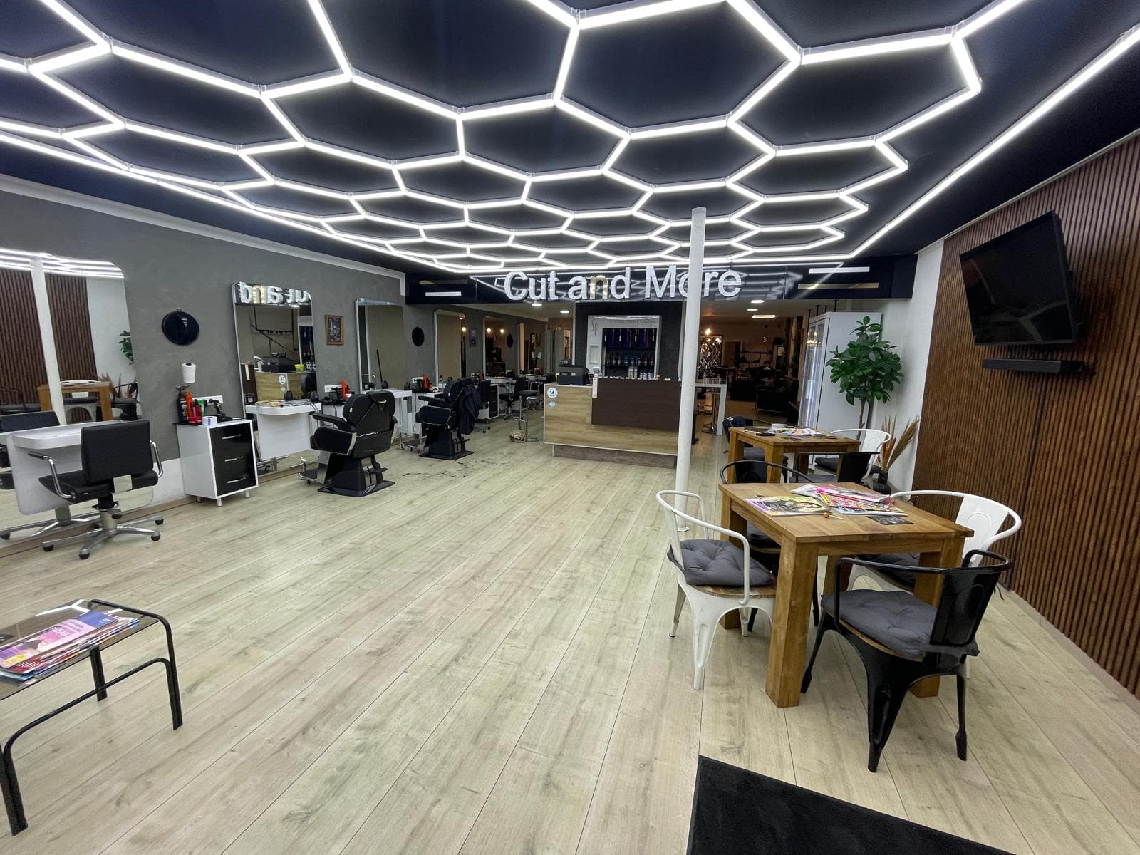 Blick in den Salon Cut and More mit beleuchteter Decke und Bedienplätzen